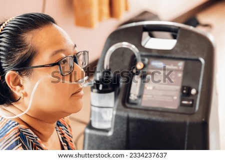 Patients woman wear oxygen inhaler device for helping breath respiratory. Patient use portable oxygen at home. Patients with respiratory disorders. portable oxygen concentrator or oxygen generator Royalty-Free Stock Photo #2334237637
