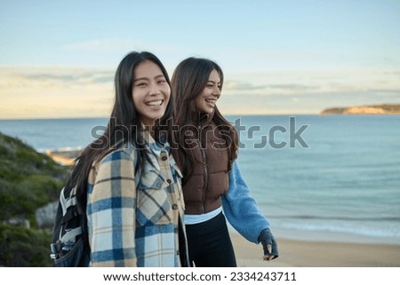 Lifestyle images of friends of multi racial backgrounds in a natural sunlit environment near sea cliffs using phones and cameras