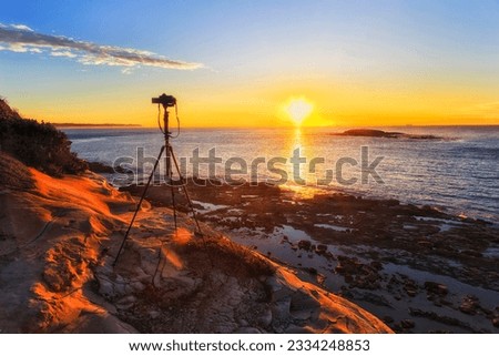 Photo Video camera shooting rising sun over Pacific ocean horizon off scenic cliffs of Swansea heas in Australia.