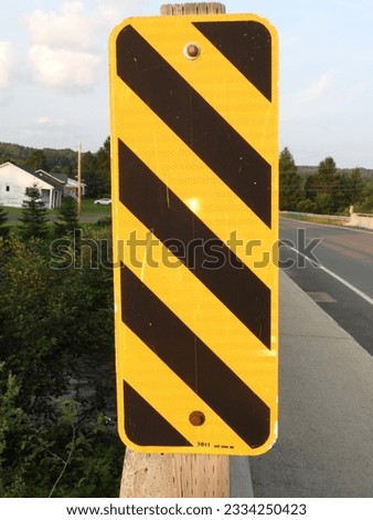 Hazard road sign close to
the edge of the road on a bridge