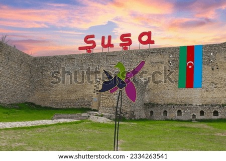 Shusha Fortress. Old brick wall and fortress in the city of Shusha. Azerbaijan flag and xaribulbul rose in the background. Entrance logo above the Shusha fortress. Karabakh, Azerbaijan