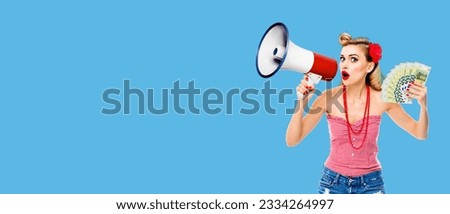 Full body portrait photo woman holding megaphone and money euro cash banknotes, shout something. Blond girl in pin up style, over bright blue color background. Female model in retro vintage concept.