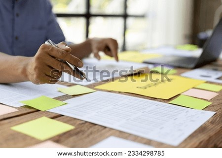 Man working on paperwork on desk, planning marketing business in office.