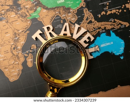 A flat lay with a magnifying glass and wooden TRAVEL on a world map background