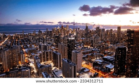An aerial view of a vibrant cityscape of Toronto including CN Tower, with tall buildings and their lights illuminated at night