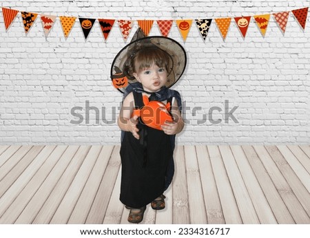 little girl, infant in witch costume with Magic cauldron and Halloween pumpkin
