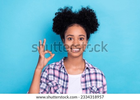 Photo of toothy beaming nice girl with perming coiffure dressed checkered shirt show okey good job isolated on blue color background