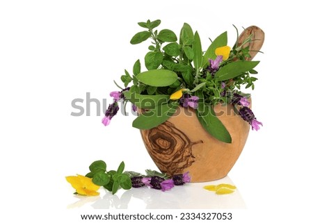 Herb leaf and flower selection in an olive wood mortar with pestle, over white background.
