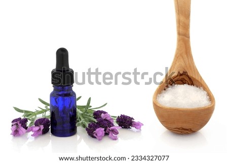 Lavender herb flowers with aromatherapy oil glass dropper bottle and olive wood ladle with sea salt, over white background.