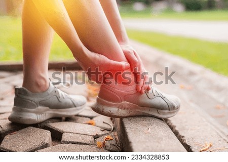 female joggers pain and discomfort after running in the public park. care and treatment for ankle injuries concept. Royalty-Free Stock Photo #2334328853
