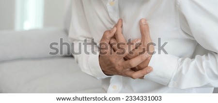 hand hold chest with heart attack symptoms, asian woman have chest pain caused by heart disease, leak, dilatation, enlarged coronary heart, press on the chest with a painful expression Royalty-Free Stock Photo #2334331003