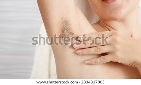 Closeup of long dark hair growing under arm of young female. Concept of hygiene, natural beauty, feminity and body hair growth Royalty-Free Stock Photo #2334337805