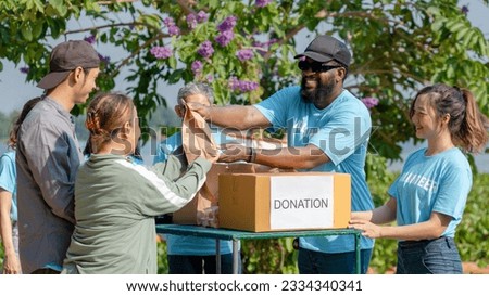 African man volunteer give some food in paper bag to poor people, raising money through donation box charitable working together to help people by donate food, clothing, support education environment Royalty-Free Stock Photo #2334340341