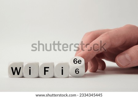 Hand turns dice and changes the expression "WiFi 6" to "WiFi 6e" on white background 
 Royalty-Free Stock Photo #2334345445