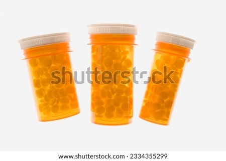 Three yellow plastic medicine bottles filled with pills. Horizontal shot. Isolated on white.