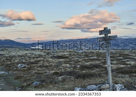 Signpost along a hiking path in the rugged landscape of the cold harsh tundra in Dovrefjell national park in the highlands of central Norway Royalty-Free Stock Photo #2334367353