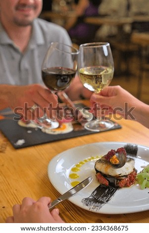 Romantic Getaway: Young Couple Enjoying a Meal at a Restaurant during Well-Deserved Vacation in Barcelona, Delighting in Beef Tenderloin and Fish Fillet, Toasting with Joy
