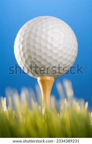 Studio shot of a golfball on a tee in grass.