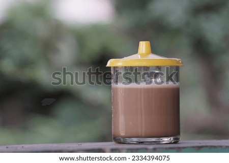 a glass of coffee latte with yellow cap