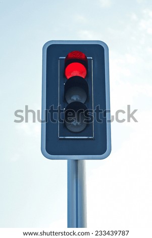 Closeup of a red traffic light with blue skies in the background