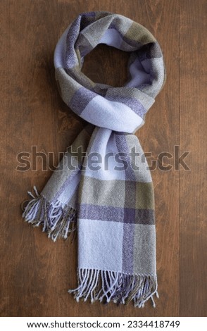 Scarf of purple, olive and lilac color on the wooden table, vertical format. Concept of neckwear, neckcloth, warm accessories Royalty-Free Stock Photo #2334418749