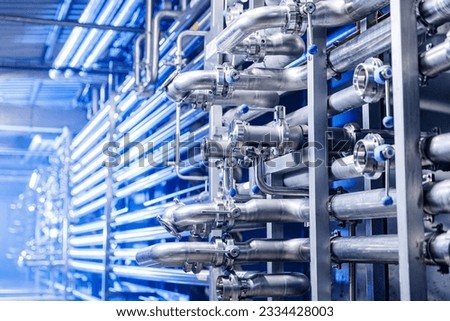 Pipes stainless steel brewing equipment, large reservoirs or tanks in modern beer factory. Brewery production concept, industrial blue background. Royalty-Free Stock Photo #2334428003