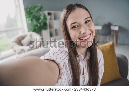 Photo of sweet cheerful young girl wear striped shirt tacking selfie showing room tour indoors apartment