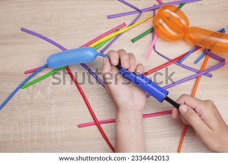 hands holding an air pump, inflate a balloon for making crafts, toys Royalty-Free Stock Photo #2334442013