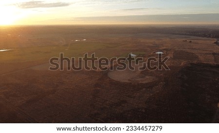 Aerial drone view of African looking nature landscape with a field, a forest and small lakes captured during sunset golden hour.