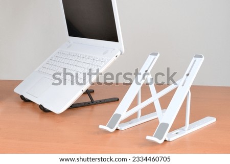 Standing laptop holder set up with notebook on desk
