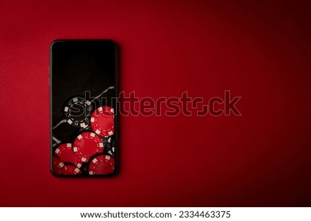 The smartphone lies on a red table with a picture of online gambling. Casino background. Online casino. Online poker.