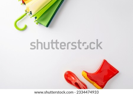 Enchanting autumn rain adventure for kids. Top-down photo featuring a colorful umbrella and bright red rubber boots on a white isolated background, perfect for text or advertising messages