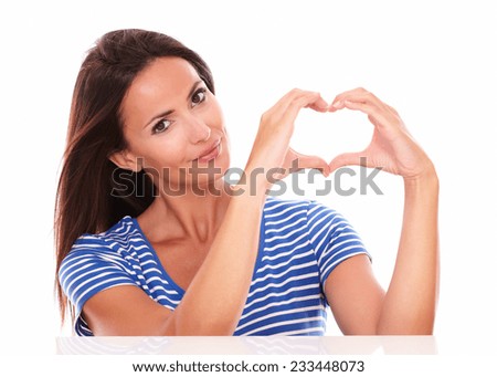 Pretty hispanic in blue t-shirt with heart sign looking at camera in white background
