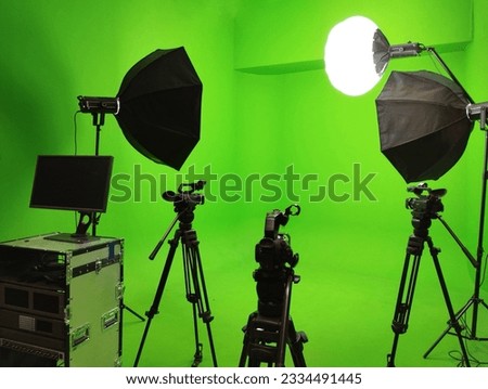 A green screen studio room used to record footage and content is equipped with a video camera and lighting system.
