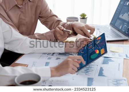 Analyst team colleague discuss financial data on digital dashboard, analyzing charts graph display on laptop and tablet screen. Modern office use business intelligence to plan marketing. Enthusiastic