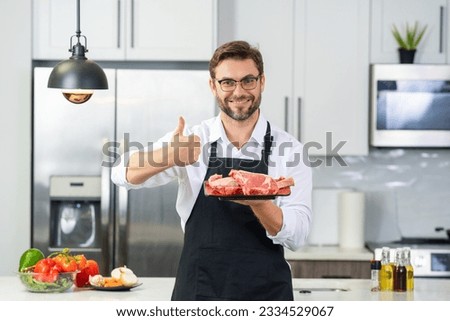 Chef cooking raw meat fillet in the kitchen. Restaurant menu concept. Male portrait of chef man hold meat in the kitchen. Raw meat fillet for advertising. Royalty-Free Stock Photo #2334529067