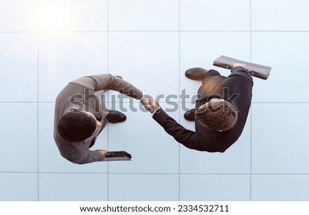 Business partners shaking hands as a symbol of unity, view from the top