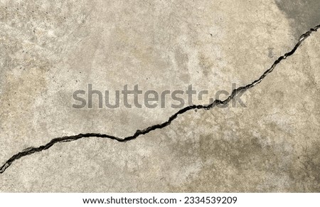 a photography of a crack in the concrete shows a crack in the ground, crack in concrete with a fire hydrant in the middle.