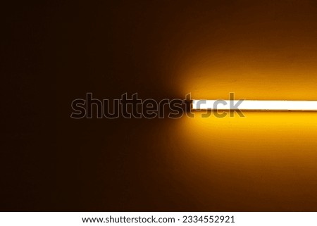 A warm white LED batten light mounted on a orange wall