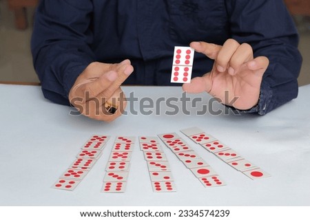 Hands playing domino cards over white table