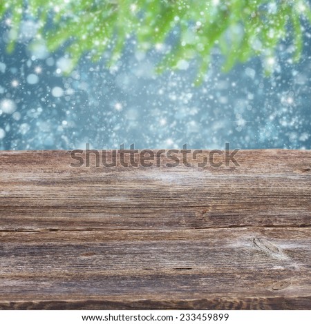 empty old wooden table with snowfall and fir tree bokeh background
