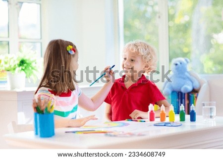 Kids paint. Child painting in white sunny study room. Little boy and girl draw rainbow. School kid doing art homework. Arts and crafts for kids. Paint on children hands. Creative little artist at 