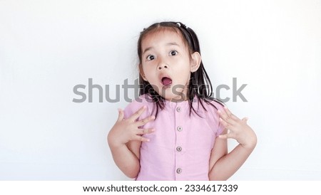 surprised beautiful little child girl in casual looking to camera on light color background. Human emotions and facial expression
