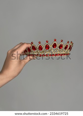 A woman holds a red crown in her hand