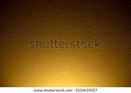 Photo background with a mural with beautiful plaster marks. It consists of a soft yellow light shining from the bottom to the top, beautiful.
