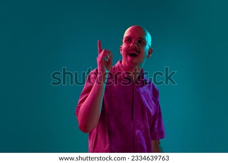 Portrait of young bald man with moustache and trendy unglasses generating creative ideas against cyan studio background in neon light. Concept of human emotions, facial expression, lifestyle