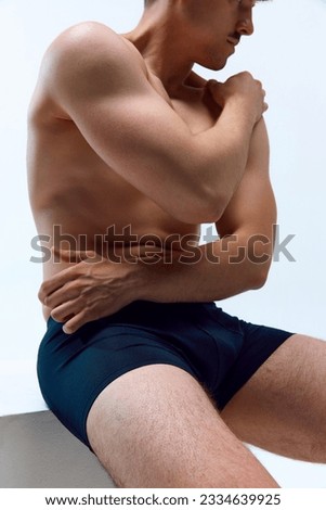 Cropped image of young man with strong, sportive, muscular body posing shirtless in underwear against white studio background. Concept of man's beauty, sportive and healthy lifestyle, athletic body Royalty-Free Stock Photo #2334639925