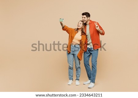 Full body young couple two friends family man woman wear casual clothes together do selfie shot on mobile cell phone post photo on social network isolated on pastel plain light beige color background Royalty-Free Stock Photo #2334643211