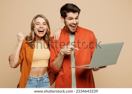 Young couple two friends family IT man woman wearing casual clothes looking camera hold use work on laptop pc computer together do winner gesture isolated on pastel plain light beige color background Royalty-Free Stock Photo #2334643239