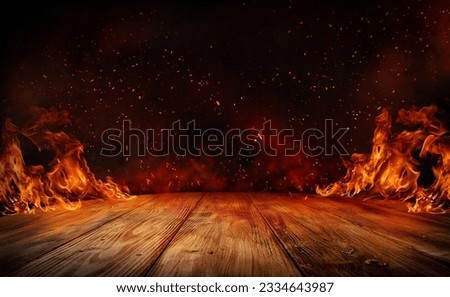 wooden table with Fire burning at the edge of the table, fire particles, sparks, and smoke in the air, with fire flames on a dark background to display products	 Royalty-Free Stock Photo #2334643987